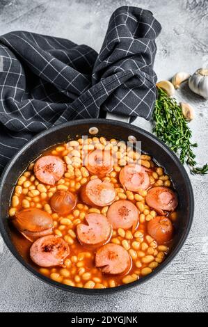 Haricots avec saucisses, sauce tomate dans une casserole. Arrière-plan blanc. Vue de dessus Banque D'Images