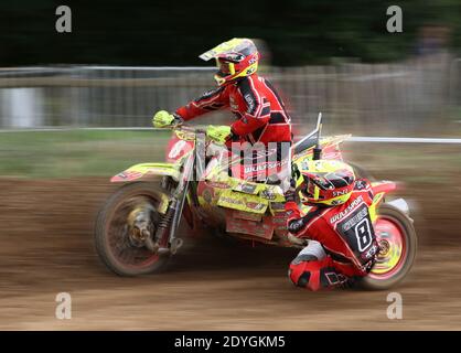 des tenues de side-car volent autour d'un bens sur une piste de motocross comme ils prennent un virage Banque D'Images