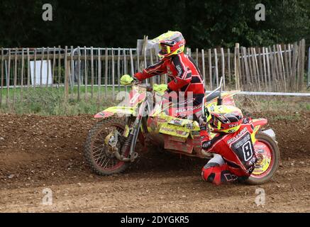 des tenues de side-car volent autour d'un bens sur une piste de motocross comme ils prennent un virage Banque D'Images