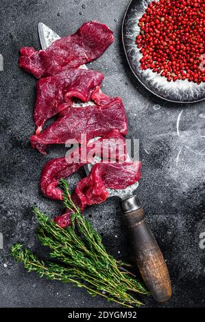 Viande crue marbrée coupée en fines bandes pour beefstroganoff. Arrière-plan noir. Vue de dessus Banque D'Images