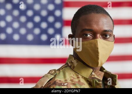 Portrait de l'homme afro-américain en masque de protection regardant Caméra debout contre le drapeau américain Banque D'Images
