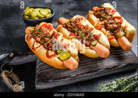 Hot dogs avec différentes garnitures. Arrière-plan en bois sombre. Vue de dessus Banque D'Images