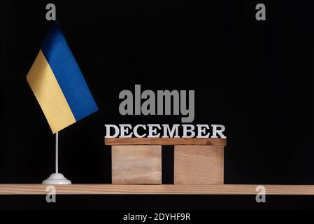 Calendrier en bois de décembre avec drapeau ukrainien sur fond noir. Dates en Ukraine en décembre Banque D'Images