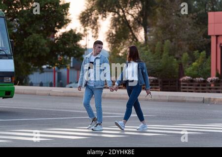 Un couple affectueux traverse la rue en tenant les mains. Photo pleine grandeur. Banque D'Images