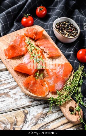 Tranches de saumon fumé aux épices et aux herbes sur la planche à découper. Arrière-plan blanc. Vue de dessus Banque D'Images