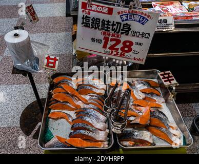 Des morceaux de saumon fileté sont exposés à la vente dans deux bacs métalliques sur un comptoir de poisson dans un supermarché à Nishiizu-Cho, préfecture de Shizuoka, Japon ; un panneau fait la promotion du saumon d'élevage décongelé du Chili comme offre du jour à 128 yens l'unité. Banque D'Images