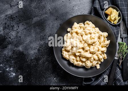 Mac et fromage. Pâtes de macaroni de style américain, sauce cheesy. Arrière-plan en bois noir. Vue de dessus. Copier l'espace Banque D'Images