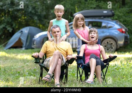 De jeunes parents heureux et leurs enfants se reposent ensemble sur le camping en été. Banque D'Images