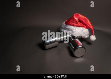 Haltères remise en forme rouge chapeau du père noël sur fond noir Banque D'Images