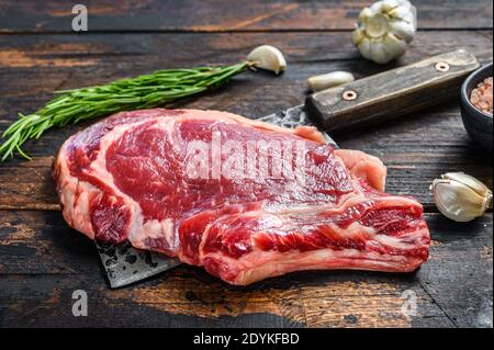 Steak de bœuf sur un cale-viande. Bœuf de marbre brut noir Angus, ribeye. Arrière-plan en bois sombre. Vue de dessus Banque D'Images