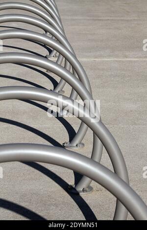 Une rangée de porte-vélos ronds vides en métal sur un trottoir en béton. Banque D'Images