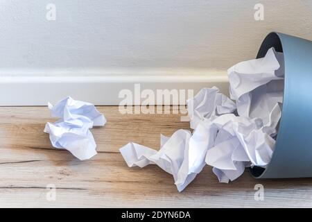 Papier poubelle. Papier froissé tombant dans le bac de recyclage, a été jeté dans le bac à paniers, débordant le papier de rebut dans le bac à déchets de bureau ancien arrière-plan en bois vue latérale avec l'espace de copie. Photo de haute qualité Banque D'Images