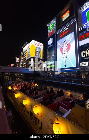 Panneaux d'affichage éclairés sur le pont bondé d'Ebisubashi et bateau de croisière sur le canal de Dotonbori la nuit. Banque D'Images