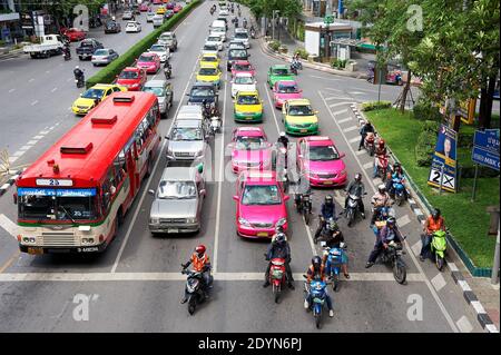 Voitures, taxis et motos colorés s'arrêtant à une intersection pendant les heures de pointe dans le centre-ville de Bangkok, en Asie Banque D'Images