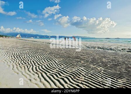 Ripples à la plage vide de White Beach sur Boracay Island, Philippines. Seulement peu de personnes et de voiliers sont présents, avec le ciel bleu comme arrière-plan Banque D'Images