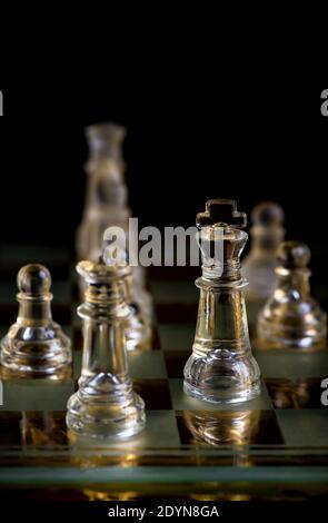 pièces d'échecs en verre à bord dans l'obscurité Banque D'Images