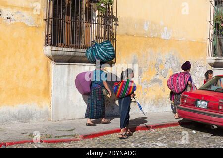 Antigua, Guatemala Groupe de femmes et de filles autochtones transportant des paquets dans la rue. Banque D'Images