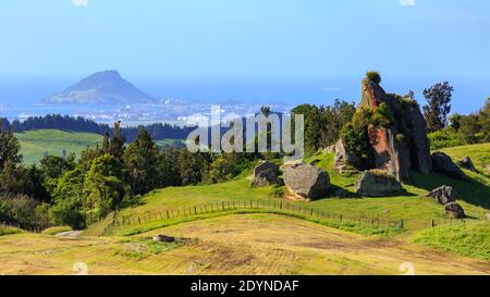 Vue sur le mont Maunganui dans la baie de Plenty, Nouvelle-Zélande, depuis les collines environnantes. Un affleurement rocheux domine le premier plan Banque D'Images