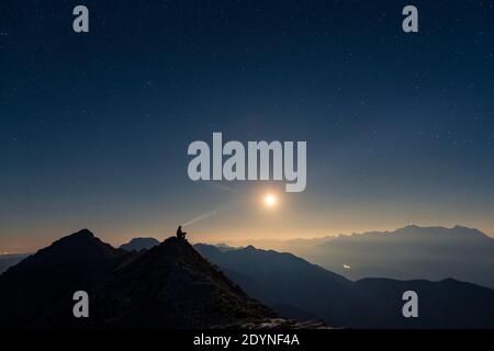 Alpiniste sur crête de sommet avec pleine lune et ciel étoilé, en arrière-plan Alpes Ammergau, Reutte, Alpes Ammergau, Tyrol, Autriche Banque D'Images