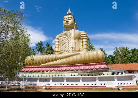 DIKWELLA, SRI LANKA - 17 FÉVRIER 2020 : sculpture géante d'un Bouddha assis (Bouddha avec une maison sur son dos) par temps ensoleillé. Temple bouddhiste Wewrukan Banque D'Images