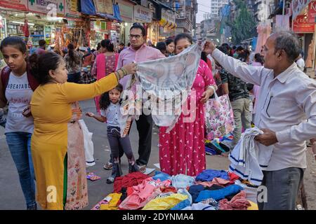 Une famille indienne magasiner et négocier pour des vêtements dans une cabine de vêtements en plein air, dans la zone de marché de Bhuleshwar, Mumbai, Inde Banque D'Images