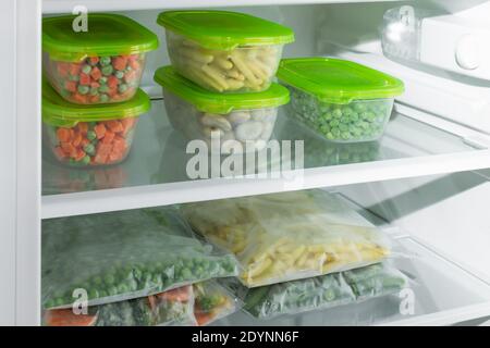 Contenants et sacs en plastique contenant différents légumes surgelés au réfrigérateur. Légumes conservés. Une alimentation saine. Banque D'Images