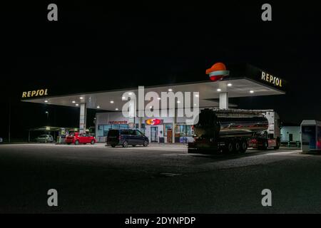 Station-service de la compagnie pétrolière Repsol avec un camion-citerne et deux voitures fournissant du carburant la nuit. Banque D'Images