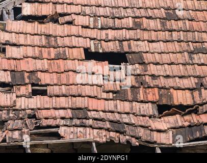 Vieux toit en brique rouge usé avec carreaux manquants Banque D'Images