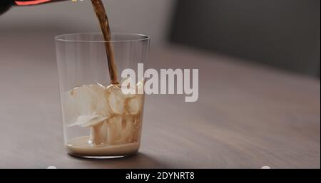 verser le cola dans le verre à verre avec glace sur la table en noyer avec espace de copie, photo large Banque D'Images