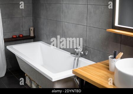 Salle de bains en béton avec baignoire, lavabo et grand miroir. Banque D'Images