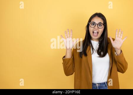 Jeune belle femme portant un blazer sur fond jaune isolé montrer et pointer vers le haut avec les doigts numéro dix tout en souriant confiant et hap Banque D'Images