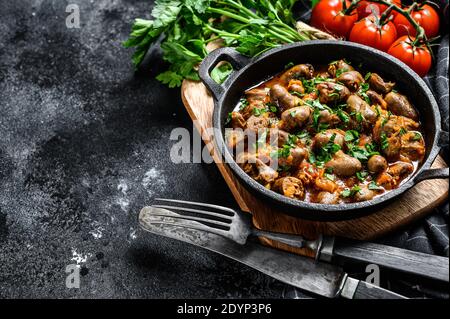 Cœurs de foie de poulet cuits dans la casserole en fonte. Arrière-plan noir. Vue de dessus. Copier l'espace Banque D'Images