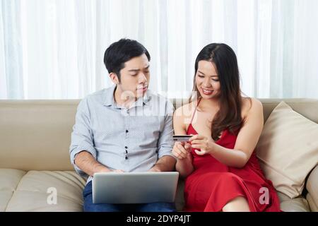 Couple multiethnique positif avec carte de crédit shopping ensemble, commander la livraison de nourriture ou des cadeaux pour Noël Banque D'Images