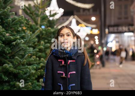 Jolie petite fille à l'extérieur dans un centre-ville à Noël Banque D'Images