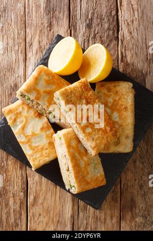 Murtabak est une crêpe farcie ou un pain poêlé avec de la viande, des œufs et des oignons verts dans le tableau sur la table. Vue verticale du dessus Banque D'Images