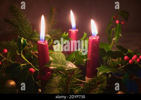 Table de Noël naturelle avec trois bougies rouges, lierre, houx et pin Banque D'Images