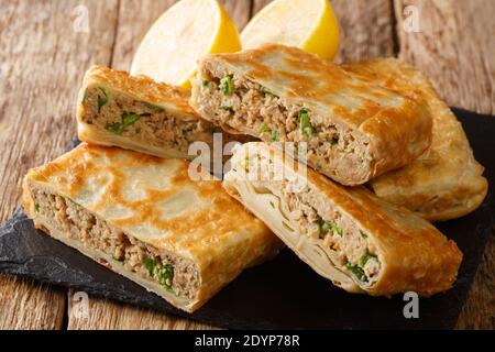 Savoureux Mutabaq Moyen-Orient pains plats frits pliés, farcis avec de la viande hachée légèrement épicée et des œufs dans le plateau sur la table. Horizonta Banque D'Images