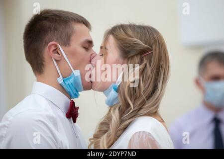 La mariée et le marié s'embrassent dans des masques médicaux. Mariage pendant le coronavirus panademia. Banque D'Images