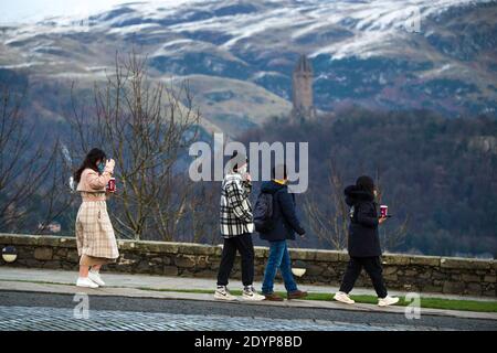 Stirling, Écosse, Royaume-Uni. 27 décembre 2020. Photo : deuxième jour du confinement de la phase 4 festive pour l'Écosse continentale. Un petit groupe de touristes chinois portant des masques de visage regardent sur le Monument Wallace du point de vue du château de Stirling qui offre des vues sur des kilomètres autour. Une petite fenêtre dans le temps émerge de l'avertissement météorologique jaune qui a été émis comme Storm Bella donne la neige chute la nuit laissant une poussière de blanc sur les collines d'Ochill. Crédit : Colin Fisher/Alay Live News Banque D'Images