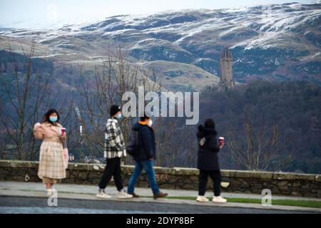 Stirling, Écosse, Royaume-Uni. 27 décembre 2020. Photo : deuxième jour du confinement de la phase 4 festive pour l'Écosse continentale. Un petit groupe de touristes chinois portant des masques de visage regardent sur le Monument Wallace du point de vue du château de Stirling qui offre des vues sur des kilomètres autour. Une petite fenêtre dans le temps émerge de l'avertissement météorologique jaune qui a été émis comme Storm Bella donne la neige chute la nuit laissant une poussière de blanc sur les collines d'Ochill. Crédit : Colin Fisher/Alay Live News Banque D'Images