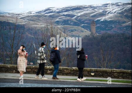 Stirling, Écosse, Royaume-Uni. 27 décembre 2020. Photo : deuxième jour du confinement de la phase 4 festive pour l'Écosse continentale. Un petit groupe de touristes chinois portant des masques de visage regardent sur le Monument Wallace du point de vue du château de Stirling qui offre des vues sur des kilomètres autour. Une petite fenêtre dans le temps émerge de l'avertissement météorologique jaune qui a été émis comme Storm Bella donne la neige chute la nuit laissant une poussière de blanc sur les collines d'Ochill. Crédit : Colin Fisher/Alay Live News Banque D'Images