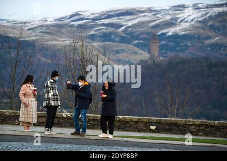 Stirling, Écosse, Royaume-Uni. 27 décembre 2020. Photo : deuxième jour du confinement de la phase 4 festive pour l'Écosse continentale. Un petit groupe de touristes chinois portant des masques de visage regardent sur le Monument Wallace du point de vue du château de Stirling qui offre des vues sur des kilomètres autour. Une petite fenêtre dans le temps émerge de l'avertissement météorologique jaune qui a été émis comme Storm Bella donne la neige chute la nuit laissant une poussière de blanc sur les collines d'Ochill. Crédit : Colin Fisher/Alay Live News Banque D'Images