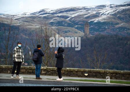 Stirling, Écosse, Royaume-Uni. 27 décembre 2020. Photo : deuxième jour du confinement de la phase 4 festive pour l'Écosse continentale. Un petit groupe de touristes chinois portant des masques de visage regardent sur le Monument Wallace du point de vue du château de Stirling qui offre des vues sur des kilomètres autour. Une petite fenêtre dans le temps émerge de l'avertissement météorologique jaune qui a été émis comme Storm Bella donne la neige chute la nuit laissant une poussière de blanc sur les collines d'Ochill. Crédit : Colin Fisher/Alay Live News Banque D'Images