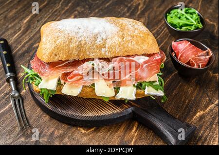 Jamon Ham Sandwich sur du pain de ciabatta avec de l'arugula et du camembert brie. fond en bois. Vue de dessus Banque D'Images