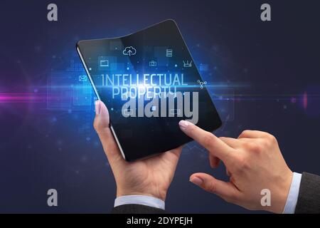 Businessman holding a smartphone pliable avec inscription de la propriété intellectuelle, la cyber sécurité concept
