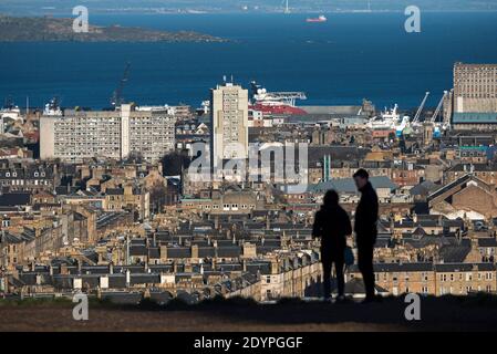 La silhouette d'un couple se tenant sur Calton Hill en regardant vers le nord en direction de Leith et du Firth of Forth à Édimbourg, en Écosse, au Royaume-Uni. Banque D'Images