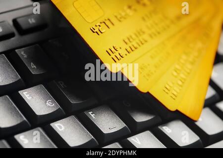 Quatre cartes de crédit dorées sur un clavier d'ordinateur noir. Concept de protection des données et des services bancaires en ligne, Internet et de sécurité financière. Banque D'Images