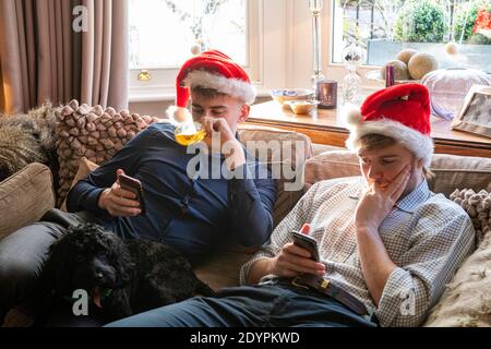 Deux garçons à Noël en chapeaux regardent leur mobile téléphones Banque D'Images