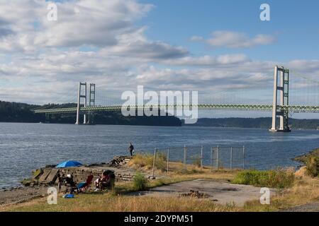 Une famille profite du coucher du soleil au parc Titlow avec vue sur le pont Tacoma Narrows. Banque D'Images