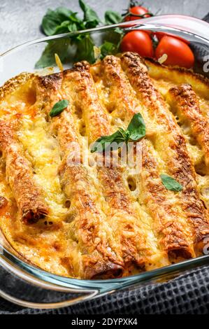 Cannelloni farcis à la sauce au béchamel. Pâtes cuites à la viande de boeuf, sauce à la crème, fromage. Arrière-plan gris. Vue du dessus Banque D'Images
